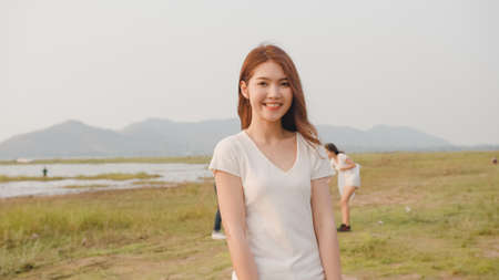 Portrait of young Asia lady volunteers help to keep nature clean up, looking at camera and smile with white garbage bags on the beach. Concept about environmental conservation pollution problems.の写真素材