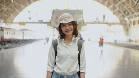 Happy Asian woman waiting the train at train station for travel in summer. Travel Thailand concept.の写真素材