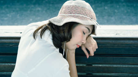 Happy teen Asian woman listening to the music with headphones and waiting in a train station summer. Travel Thailand concept.の写真素材
