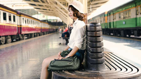 Happy Asian woman waiting the train at train station for travel in summer. Travel Thailand concept.の写真素材