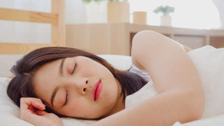 Asian woman dreaming while sleeping on bed in bedroom, Beautiful japanese female using relax time lying on bed at home. Lifestyle women using relax time at home concept.の写真素材