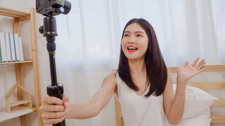 Young Asian teenager woman vlog at home, female using camera making vlog video to social media in bedroom. Lifestyle woman relax in morning at home concept.の写真素材