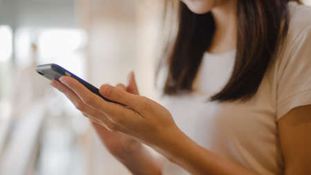 Freelance Asian women using mobile phone at office. Young Japanese Asia Girl using smartphone checking social media on the internet on the table at workplace concept.の写真素材