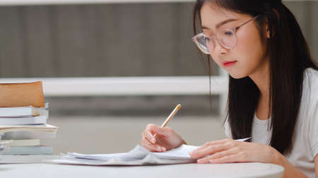 Freelance Asian women using mobile phone at office. Young Japanese Asia Girl using smartphone checking social media on the internet on the table at workplace concept.の写真素材