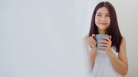 Freelance Asian women using mobile phone at office. Young Japanese Asia Girl using smartphone checking social media on the internet on the table at workplace concept.の写真素材