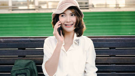 Freelance Asian women using mobile phone at office. Young Japanese Asia Girl using smartphone checking social media on the internet on the table at workplace concept.の写真素材