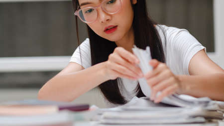 Asian student women reading books in library at university. Young undergraduate girl do homework, read textbook, study hard for knowledge and education on lecture desk at college campus.の写真素材