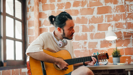 Artists producing music in their home sound studio, Asian man playing guitar and singing in living room at home. Lifestyle man relax in morning at home concept.の写真素材