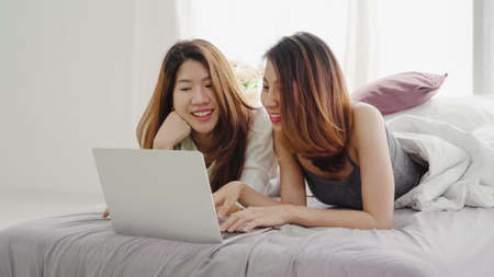 Attractive smart Asian business woman in smart casual wear working on laptop while sitting on desk while her angry manager standing angry throwing papers on office desk. Women work at office concept.の写真素材
