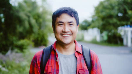 Asian hiker man trekking in forest. Young happy backpack male smiling to camera, travel nature and adventure trip, climb mountain lot of tree in spring holidays vacation concept.の写真素材