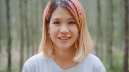 Healthy beautiful young Asian runner woman feeling happy smiling and looking to camera after running on forest trail. Lifestyle fit and active women exercise in the forest concept.の写真素材