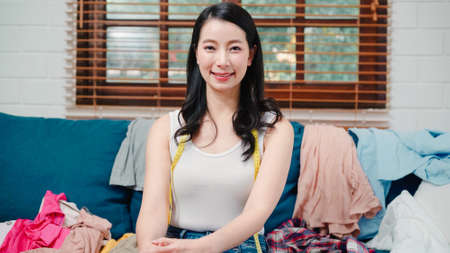 Asian influencer women using camera streaming and recording vlog video about the benefit of drinking milk and sandwiches for breakfast on sofa in living room at home for broadcast online.の写真素材