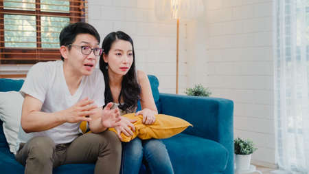 Asian couple watching television in living room at home, sweet couple enjoy love moment while lying on the sofa when relaxed at home. Lifestyle couple relax at home concept.の写真素材