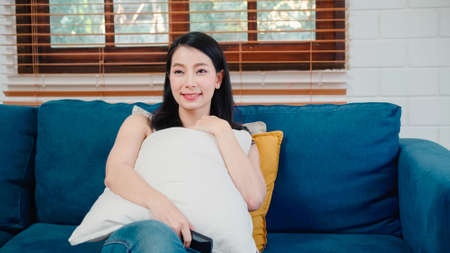 Asian influencer women using camera streaming and recording vlog video about the benefit of drinking milk and sandwiches for breakfast on sofa in living room at home for broadcast online.の写真素材