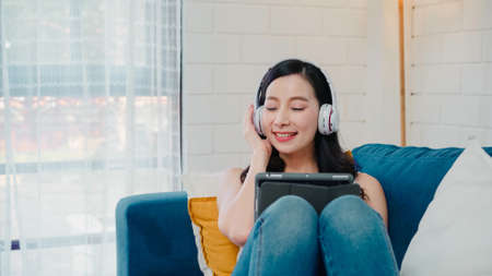 Asian influencer women using camera streaming and recording vlog video about the benefit of drinking milk and sandwiches for breakfast on sofa in living room at home for broadcast online.の写真素材