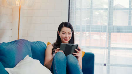 Asian influencer women using camera streaming and recording vlog video about the benefit of drinking milk and sandwiches for breakfast on sofa in living room at home for broadcast online.の写真素材