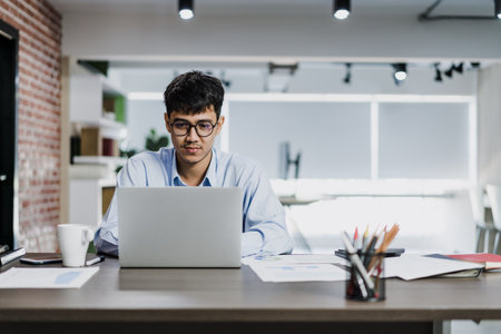 Asian creative man drawing work plan on paper board. Young professional business male think and write information reminder on paper on brick, business situation, startup in Loft office concept.の写真素材