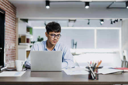 Asian creative man drawing work plan on paper board. Young professional business male think and write information reminder on paper on brick, business situation, startup in Loft office concept.の写真素材