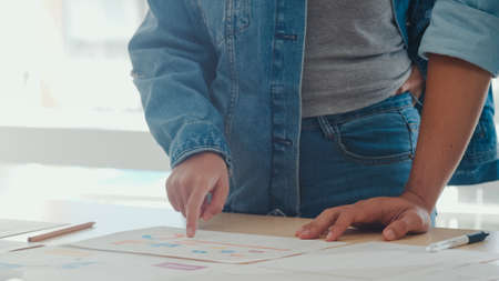 Young Asian creative team meeting working on laptop. Group of business man and woman looking document paper, discuss and think new idea, business situation, teamwork in modern office concept.の写真素材