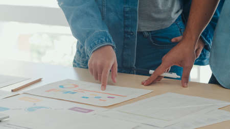 Young Asian creative team meeting working on laptop. Group of business man and woman looking document paper, discuss and think new idea, business situation, teamwork in modern office concept.の写真素材
