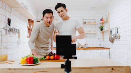 Young Asia gay couple propose at modern home, LGBTQ men happy smiling have romantic time while proposing and marriage surprise wear wedding ring in living room at house. Anniversary romantic concept.の写真素材