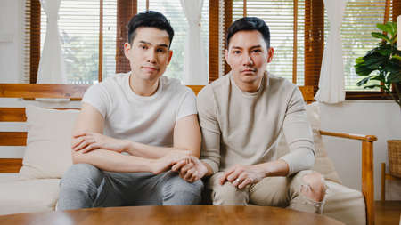 Young Asia gay couple propose at modern home, LGBTQ men happy smiling have romantic time while proposing and marriage surprise wear wedding ring in living room at house. Anniversary romantic concept.の写真素材