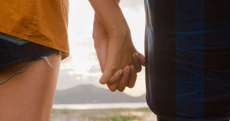 Young asia campers couple run and raised arms at campsite near beach. Happy male and female traveler success and fun when sunset in evening. Outdoor activity, adventure travel, or holiday vacation.の写真素材