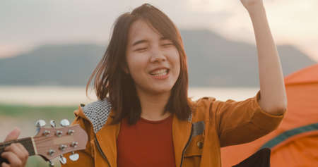 Young asia campers couple camping near seaside. Male and female traveler using smartphone vlog video and live in social media at campsite. Outdoor activity, adventure travel, or holiday vacation.の写真素材