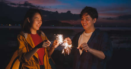 Young asia campers couple camping near seaside. Male and female traveler using smartphone vlog video and live in social media at campsite. Outdoor activity, adventure travel, or holiday vacation.の写真素材