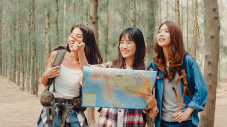 Group of young asia camper friends camping near relax enjoy moment in forest. Female traveler using smartphone taking selfie at campsite. Outdoor activity, adventure travel, or holiday vacation.の写真素材