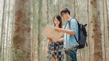 Asian hiker couple trekking in forest. Young happy backpack male and female walking enjoy her journey, travel nature and adventure trip, climb mountain lot of tree in fall holidays vacation concept.の写真素材