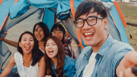 Group of Asia best friends teenagers lady dancing and drinking have fun salute toast of bottle beer enjoy party with happy moments together in campsite at night. Beautiful camping traveller concept.の写真素材
