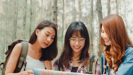 Group of young asia camper friends camping near relax enjoy moment in forest. Female traveler using smartphone taking selfie at campsite. Outdoor activity, adventure travel, or holiday vacation.の写真素材