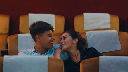 Attractive cheerful young caucasian couple laughing while watching film in movie theater. Lifestyle entertainment concept.の写真素材