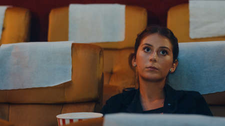 Attractive cheerful young caucasian lady laughing while watching film in movie theater. Lifestyle entertainment concept. Close up shot.の写真素材