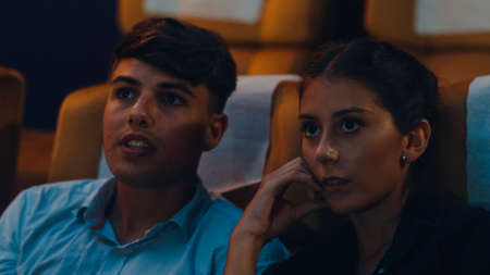 Attractive cheerful young caucasian couple laughing while watching film in movie theater. Lifestyle entertainment concept.の写真素材