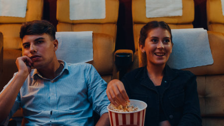 Attractive cheerful young caucasian couple laughing while watching film in movie theater. Lifestyle entertainment concept.の写真素材