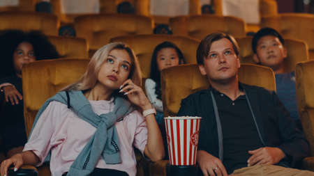 Attractive cheerful young caucasian couple laughing while watching film in movie theater. Lifestyle entertainment concept.の写真素材
