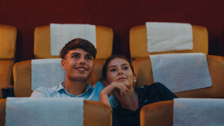 Attractive cheerful young caucasian couple kissing romantic moment while watching film in movie theater. Lifestyle entertainment concept.の写真素材