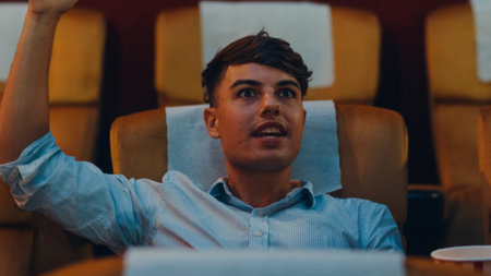 Attractive cheerful young caucasian man watching horror movie in cinema theater. Lifestyle entertainment concept. Close up shot.の写真素材