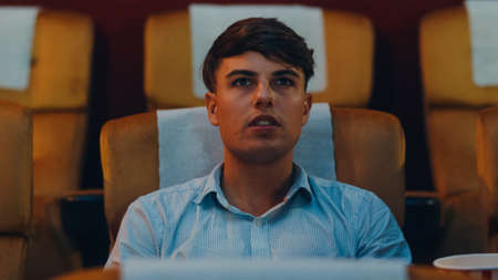 Attractive cheerful young caucasian man watching horror movie in cinema theater. Lifestyle entertainment concept. Close up shot.の写真素材