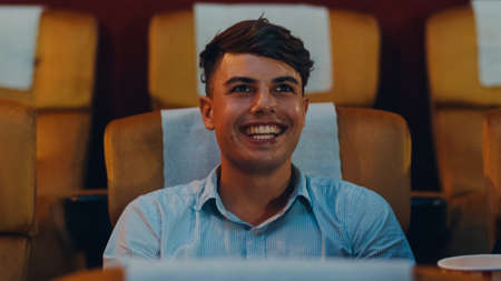 Attractive cheerful young caucasian man watching horror movie in cinema theater. Lifestyle entertainment concept. Close up shot.の写真素材