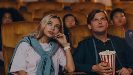 Attractive cheerful young caucasian couple laughing while watching film in movie theater. Lifestyle entertainment concept.の写真素材