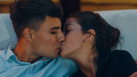Attractive cheerful young caucasian couple kissing romantic moment while watching film in movie theater. Lifestyle entertainment concept.の写真素材