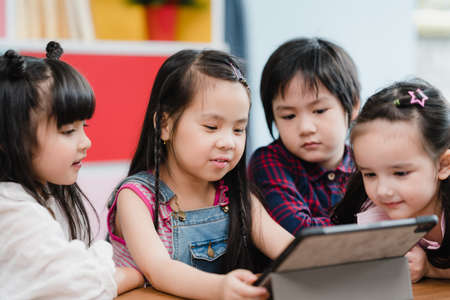 Group of children using tablet in classroom, Multi-ethnic young boys and girls happy using technology for study and play games at elementary school. Kids use technology for education concept.の写真素材