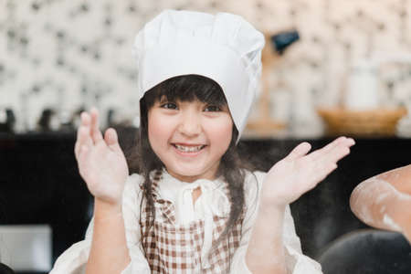 Group of children baking cake together in classroom, Multi-ethnic young boys and girls happy making dessert cooking in kitchen at school. Kids cooking at school concept.の写真素材