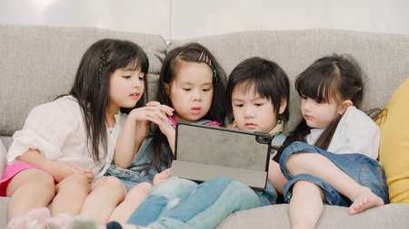 Group of children using tablet in classroom, Multi-ethnic young boys and girls happy using technology for study and play games at elementary school. Kids use technology for education concept.の写真素材