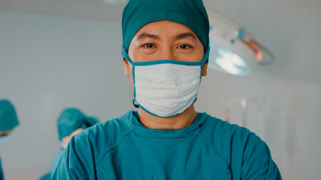 Young Asian assistants man looking at camera and smiling after performing invasive surgery on...