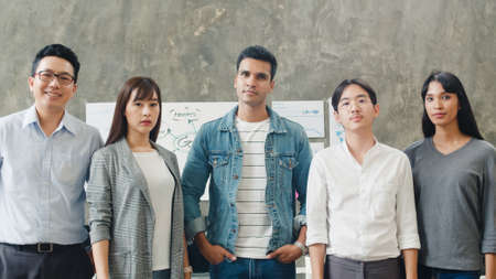 Portrait of successful creative businessman and businesswoman smart casual wear looking at camera and arms raise in modern office workplace. Diverse Asia male and female standing together at startup.の写真素材