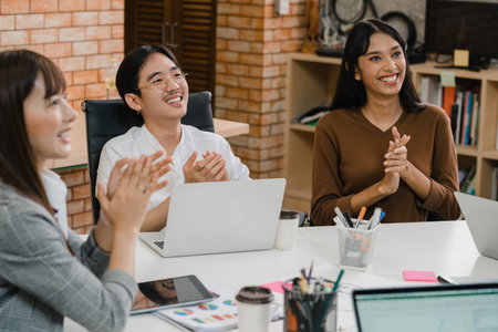Happy young Asia businessmen and businesswomen meeting brainstorming ideas about new paperwork project colleagues working together planning success strategy enjoy teamwork in small modern office.の写真素材